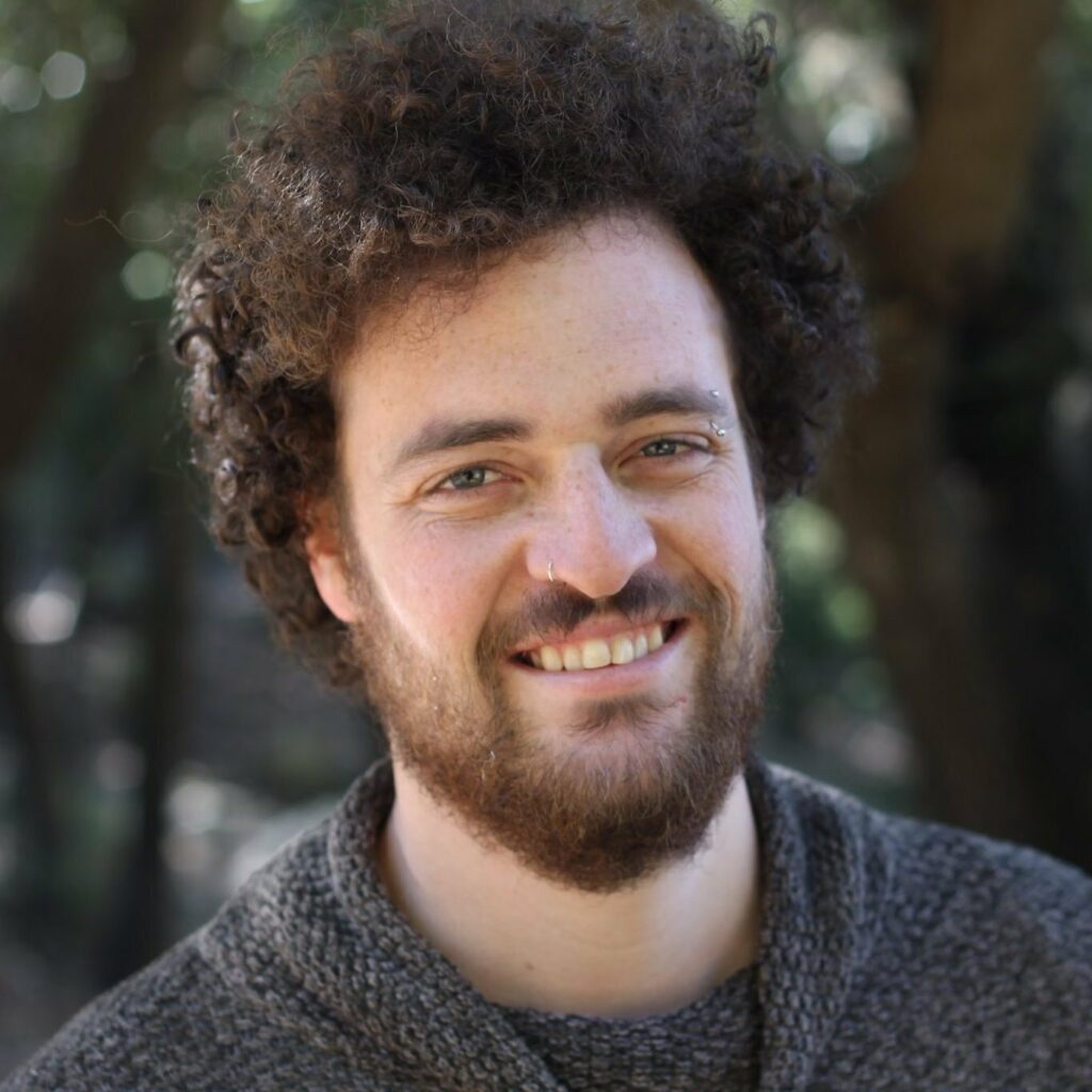 Portrait of a Avishai Karawan, a content creator, smiling outdoors, framed by trees in the background. Ideal for video editing projects involving royalty-free music and natural sound effects.