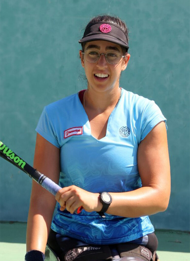 Maayan Zikri, a female tennis player, smiling and holding a racket, wearing a visor and sports attire. Perfect for content creators seeking dynamic stock footage for video editing projects.