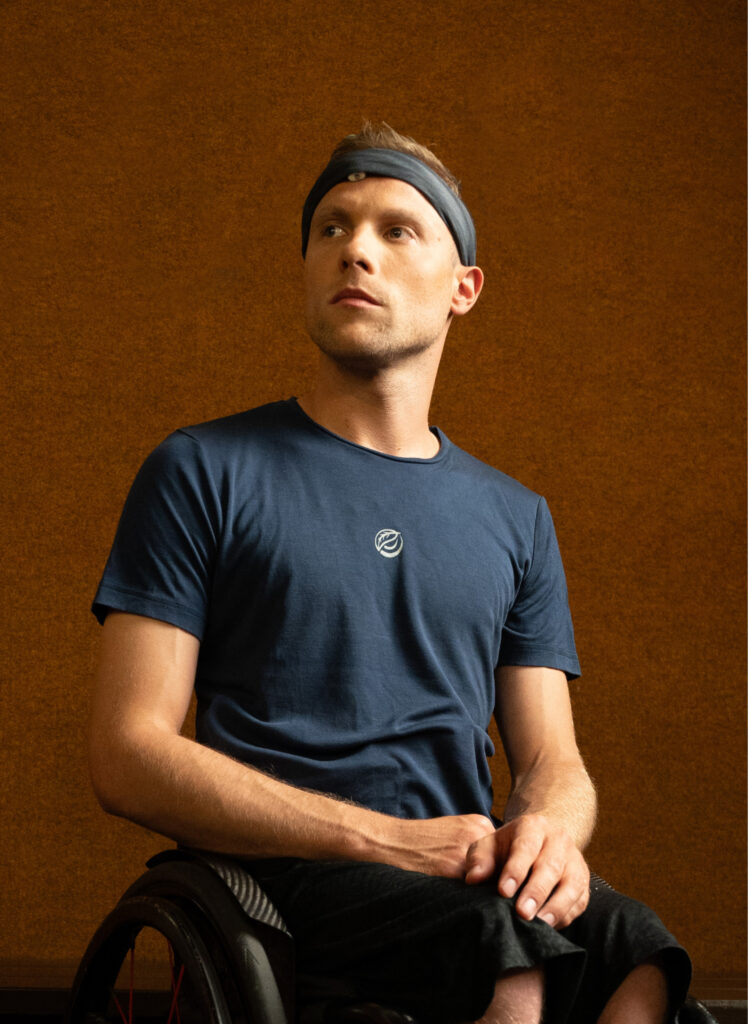 Thomas Böhme, a male athlete in a wheelchair, wearing a headband and blue t-shirt, looking upward with a thoughtful expression. Perfect for video editors and content creators working on motivational projects.